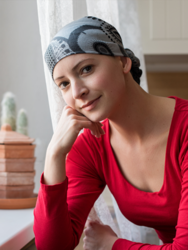 Female cancer survivor wearing a head scarf looking positive.